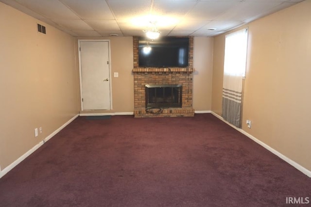 unfurnished living room featuring dark colored carpet, a drop ceiling, and a fireplace