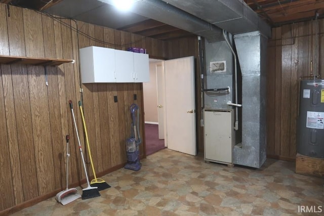 basement featuring heating unit, electric water heater, and wood walls