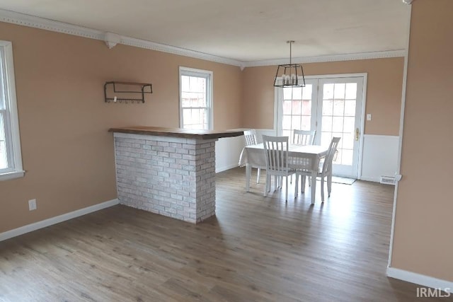 unfurnished dining area featuring hardwood / wood-style floors, ornamental molding, and a healthy amount of sunlight