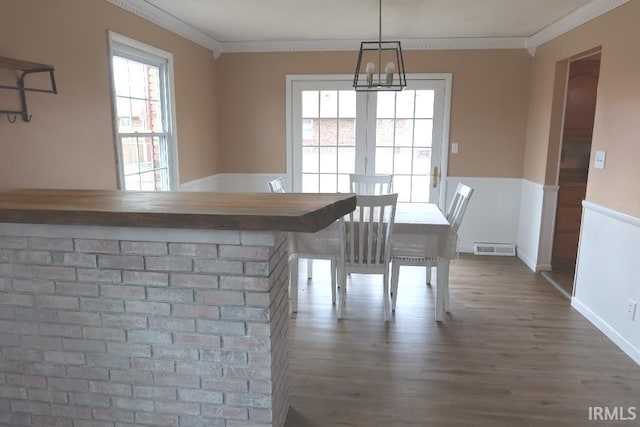 unfurnished dining area featuring hardwood / wood-style floors, crown molding, a wealth of natural light, and a chandelier