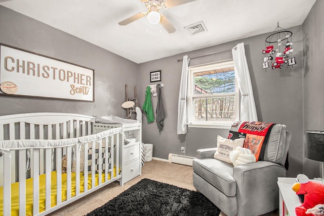 carpeted bedroom featuring a crib, ceiling fan, and baseboard heating