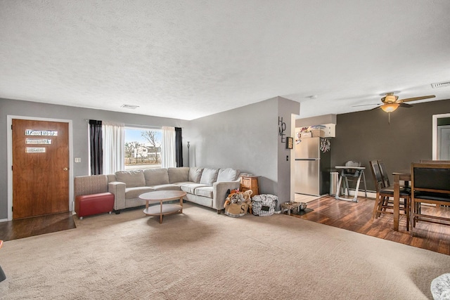 living room featuring ceiling fan, carpet flooring, and a textured ceiling