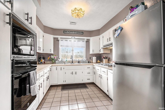 kitchen with sink, a textured ceiling, stainless steel appliances, and white cabinets