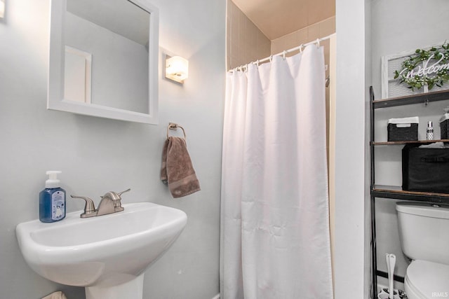 bathroom featuring sink, curtained shower, and toilet