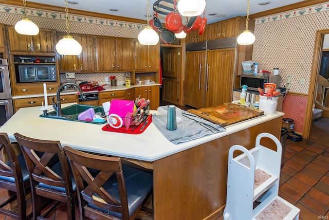 kitchen with pendant lighting, stainless steel appliances, sink, and a center island with sink