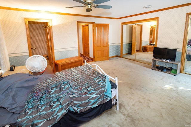 carpeted bedroom featuring ornamental molding, ceiling fan, and a closet