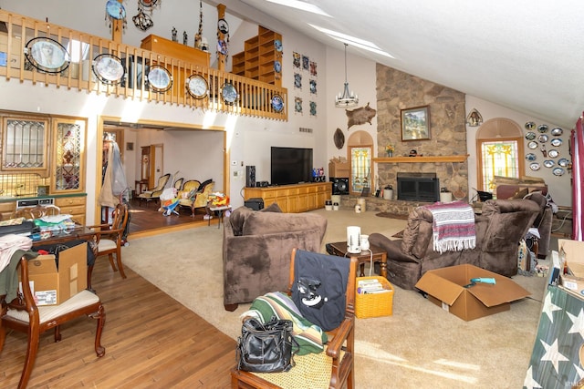 living room featuring wood-type flooring, a stone fireplace, and high vaulted ceiling