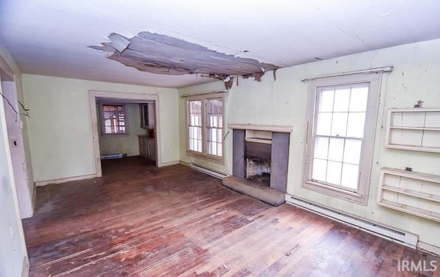 unfurnished living room with a baseboard radiator, wood-type flooring, and a wealth of natural light