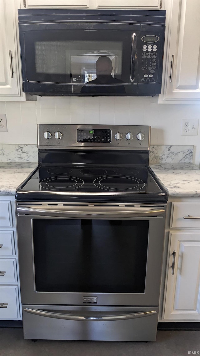 kitchen with tasteful backsplash, white cabinetry, light stone countertops, and stainless steel electric range