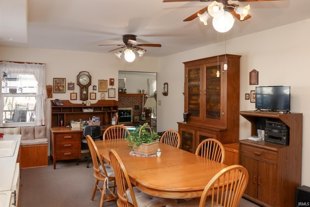 carpeted dining space featuring ceiling fan and a fireplace