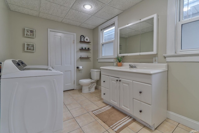 bathroom with washing machine and clothes dryer, toilet, a paneled ceiling, vanity, and tile patterned flooring