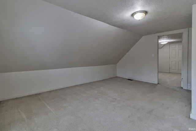 bonus room with light colored carpet, vaulted ceiling, and a textured ceiling