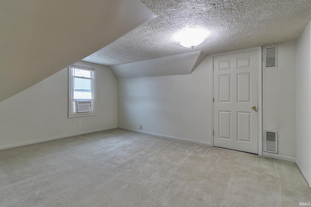 additional living space featuring lofted ceiling, cooling unit, light colored carpet, and a textured ceiling