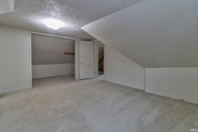 additional living space with light colored carpet and a textured ceiling