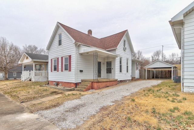 view of front facade with central AC, a front yard, a carport, and a porch