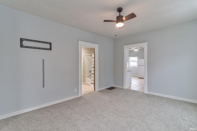 unfurnished bedroom featuring light colored carpet, ensuite bathroom, ceiling fan, and white refrigerator