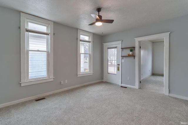 carpeted empty room with ceiling fan and a textured ceiling