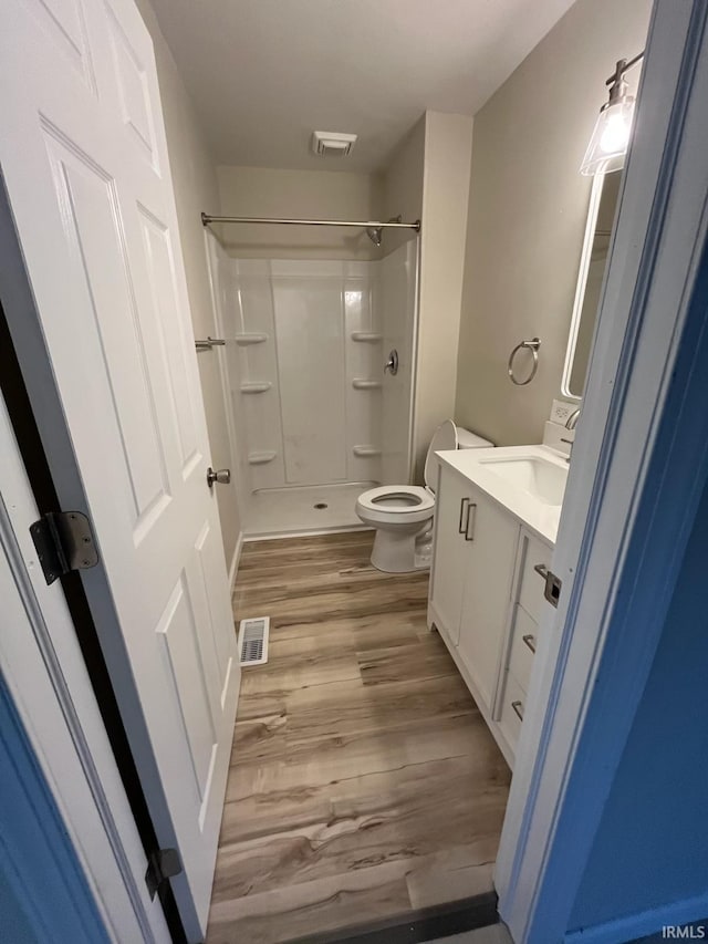 bathroom featuring vanity, toilet, hardwood / wood-style floors, and walk in shower