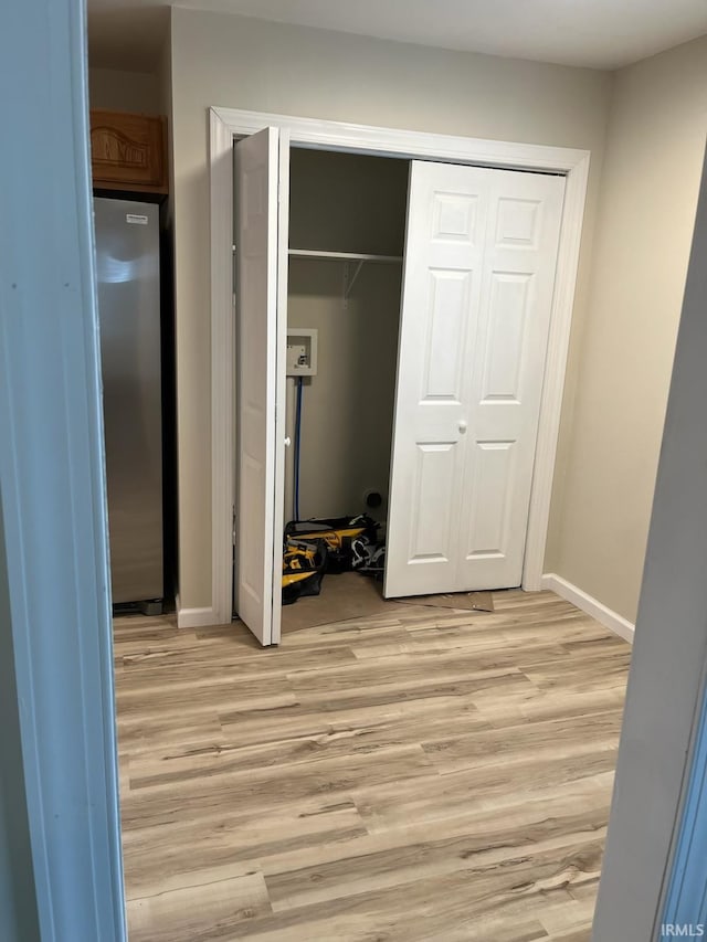 unfurnished bedroom featuring stainless steel refrigerator, a closet, and light wood-type flooring