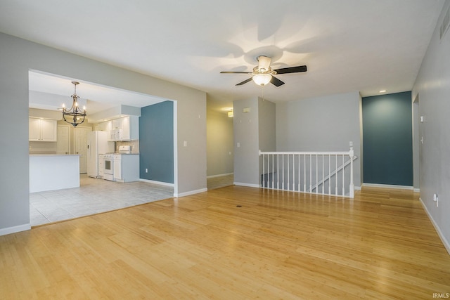 unfurnished living room featuring ceiling fan with notable chandelier and light wood-type flooring