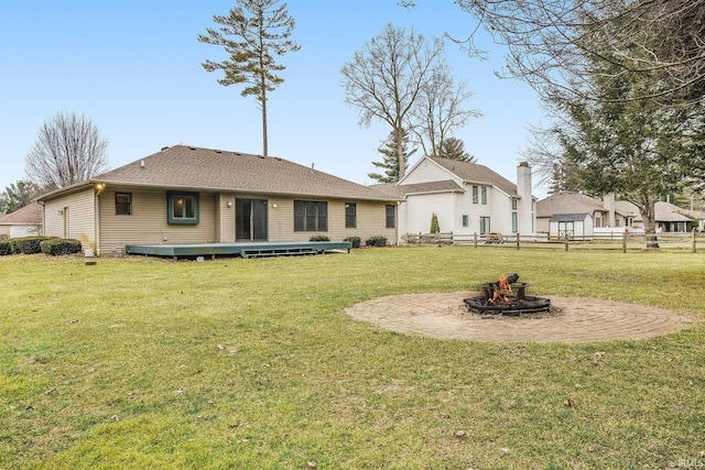 back of property featuring a yard and an outdoor fire pit