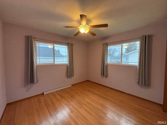 unfurnished room featuring a baseboard heating unit, ceiling fan, a healthy amount of sunlight, and light wood-type flooring