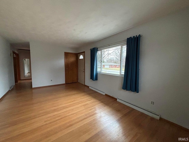 unfurnished room with light hardwood / wood-style floors and a baseboard heating unit