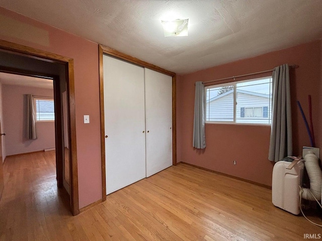 unfurnished bedroom featuring a textured ceiling, light hardwood / wood-style floors, and a closet