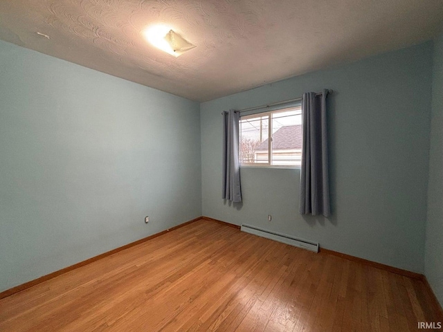 spare room with hardwood / wood-style flooring, a baseboard radiator, and a textured ceiling