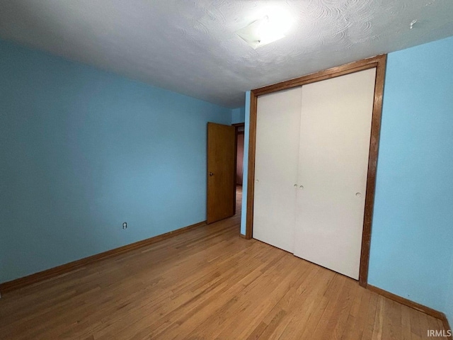 unfurnished bedroom featuring a textured ceiling, light hardwood / wood-style floors, and a closet