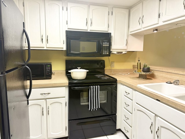 kitchen featuring white cabinets, light tile patterned floors, sink, and black appliances