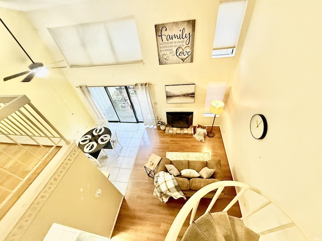 living room with a towering ceiling, hardwood / wood-style floors, and ceiling fan