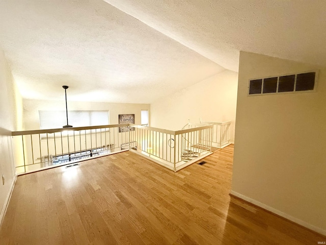 interior space with ceiling fan, lofted ceiling, hardwood / wood-style floors, and a textured ceiling