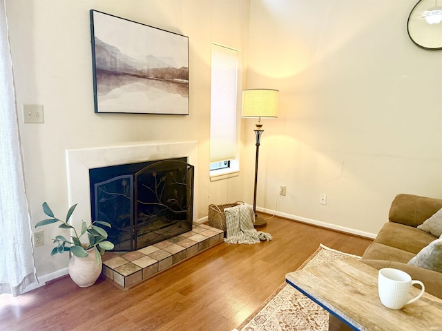 living room with a tiled fireplace and hardwood / wood-style floors