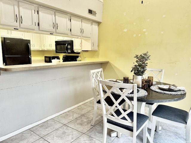 kitchen featuring white cabinets, kitchen peninsula, light tile patterned floors, and black appliances