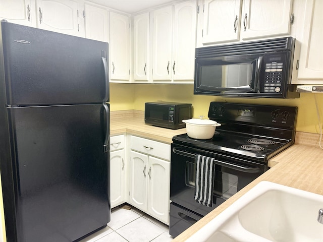 kitchen with white cabinets, sink, light tile patterned floors, and black appliances