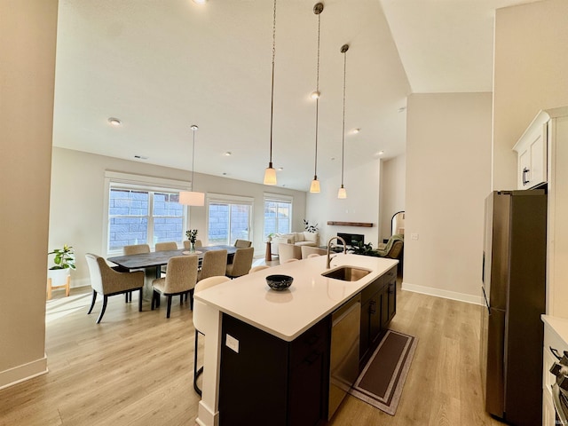 kitchen with white cabinetry, sink, hanging light fixtures, a kitchen island with sink, and stainless steel appliances