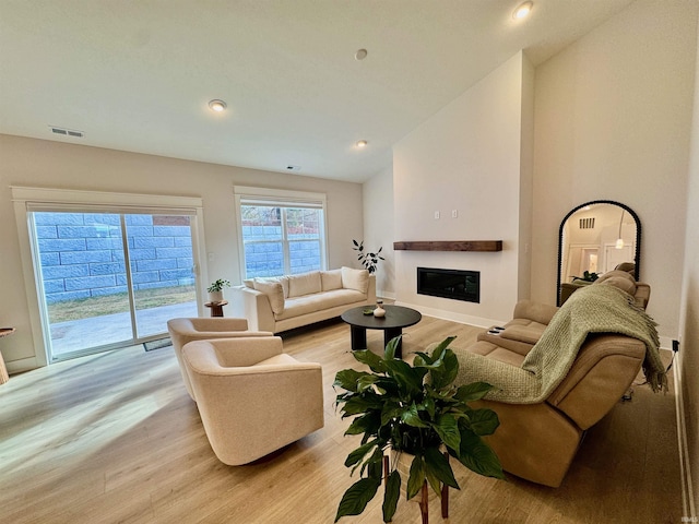 living room with light hardwood / wood-style flooring and high vaulted ceiling