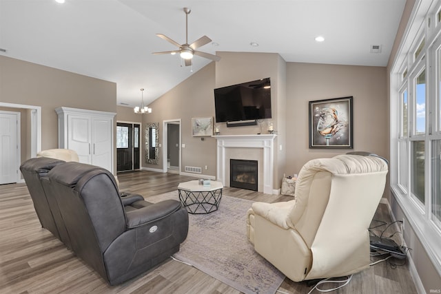 living room with ceiling fan with notable chandelier, high vaulted ceiling, a wealth of natural light, and light wood-type flooring