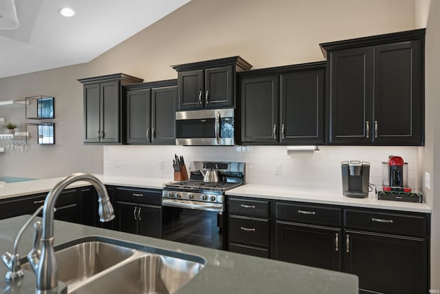 kitchen featuring vaulted ceiling, stainless steel appliances, sink, and decorative backsplash