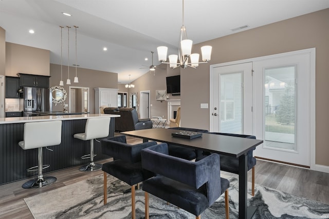 dining area with dark hardwood / wood-style flooring, ceiling fan with notable chandelier, and lofted ceiling