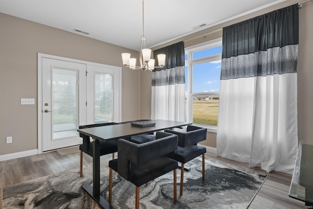 dining space with hardwood / wood-style floors and a notable chandelier