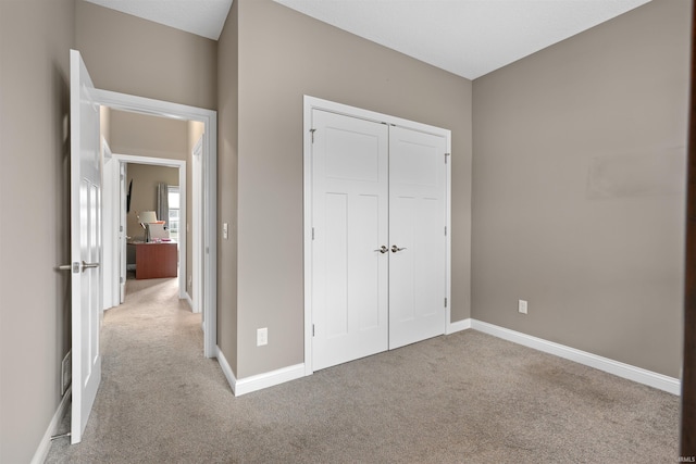 unfurnished bedroom featuring light colored carpet and a closet