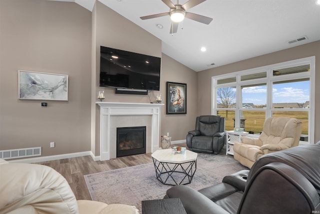 living room with a tiled fireplace, high vaulted ceiling, light hardwood / wood-style floors, and ceiling fan