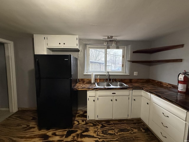 kitchen featuring black fridge, sink, and white cabinets