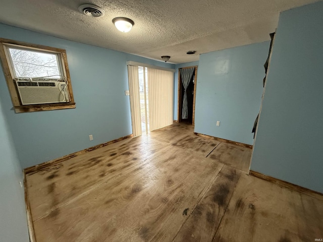 unfurnished room featuring wood-type flooring, cooling unit, and a textured ceiling