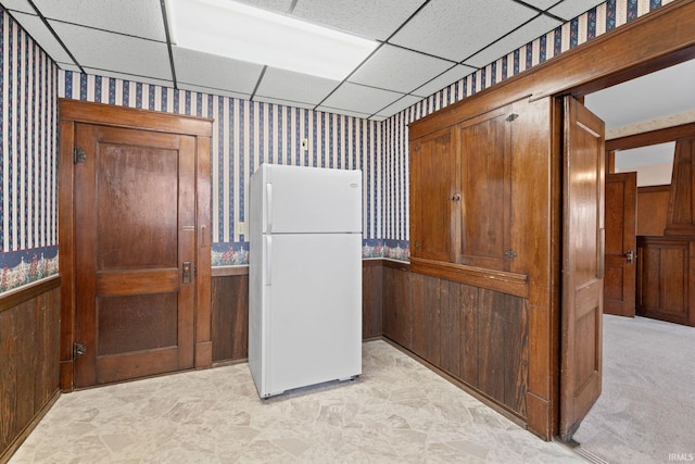 kitchen featuring a paneled ceiling, wooden walls, and white refrigerator