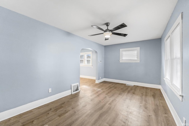 unfurnished room featuring a healthy amount of sunlight, wood-type flooring, and ceiling fan