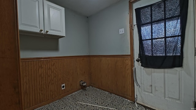 clothes washing area with wooden walls, cabinets, and hookup for an electric dryer