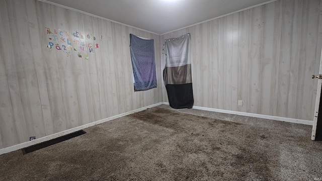 carpeted empty room featuring wooden walls and ornamental molding